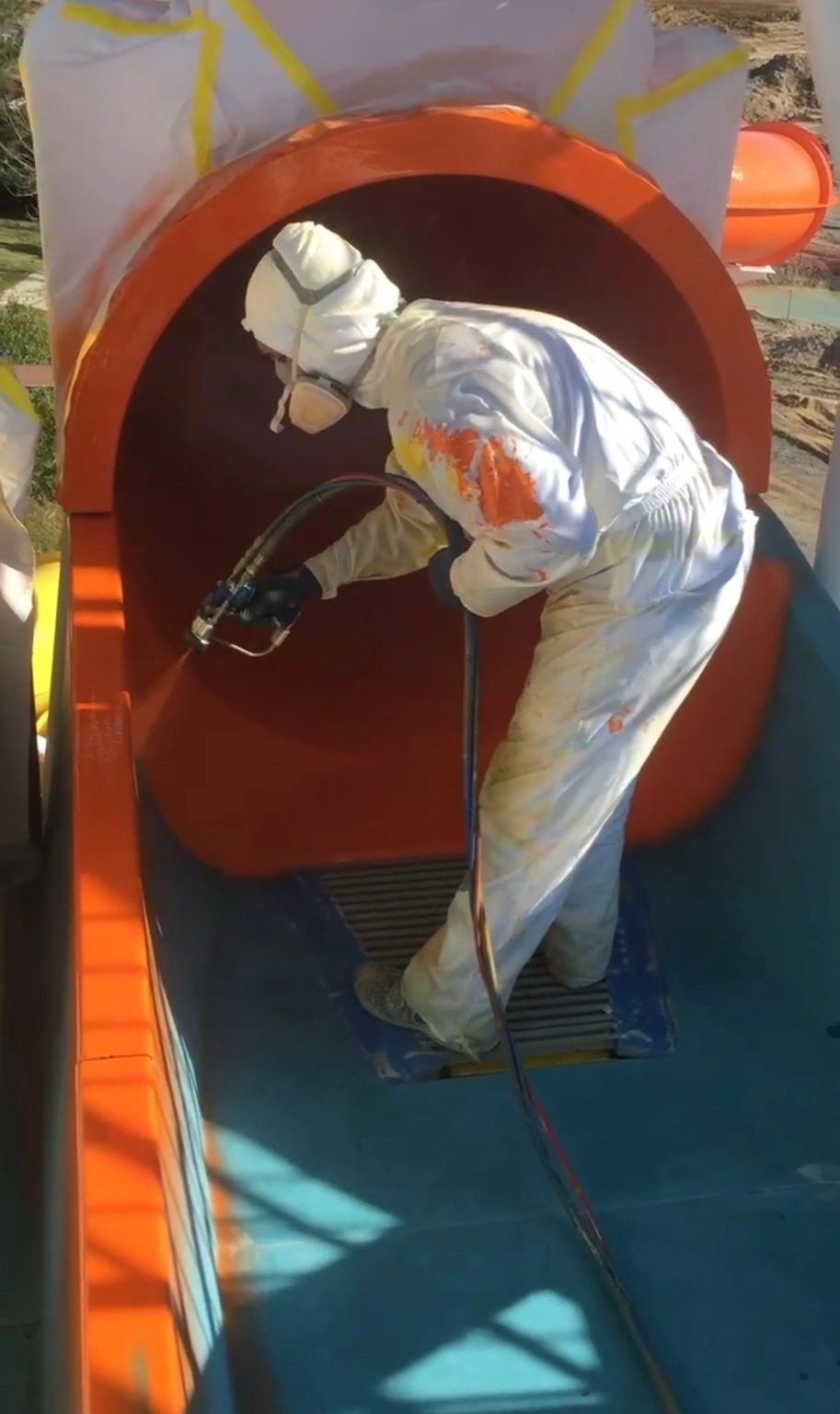 Technician spraying gel coat inside a slide